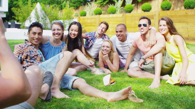 Cheerful group of young friends relaxing outdoors together and taking photos