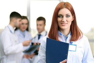 Fototapeta premium Beautiful young doctor with team in conference room