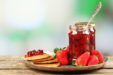 Jars of strawberry jam with berries and wafers