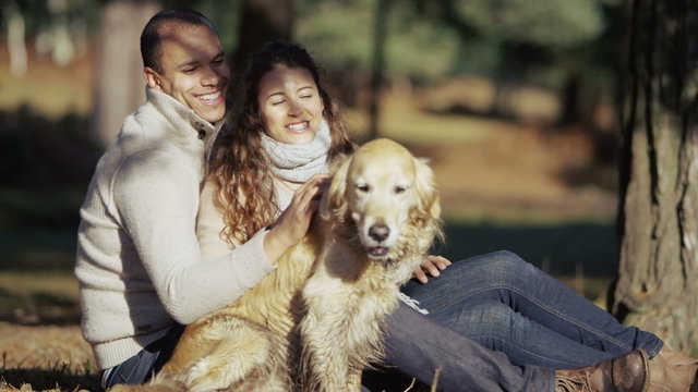 Young couple in love enjoy spending time outdoors with their lovable pet dog
