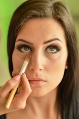 Make-up artist applying bright base color eyeshadow on model's e