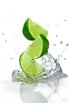 Three slices of lime falling into water