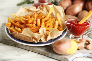 Tasty french fries on cutting board, on wooden table background