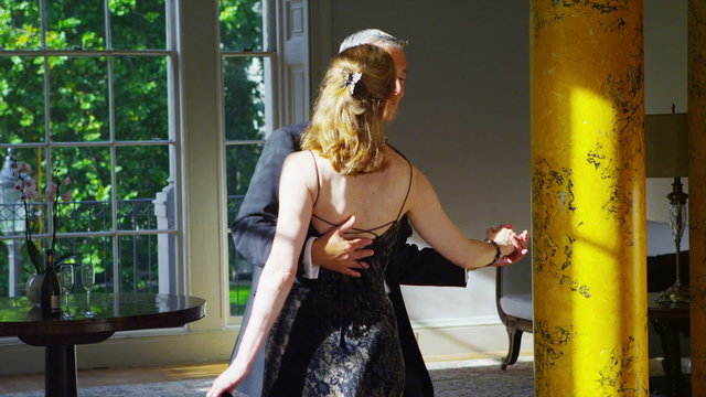 Happy romantic mature couple in evening wear dancing together in elegant home