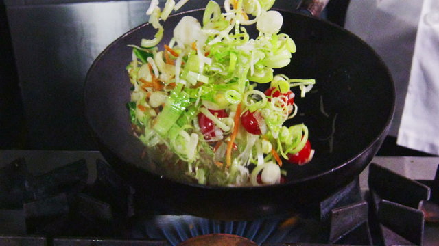 Professional chef in a commercial kitchen cooking flambe style