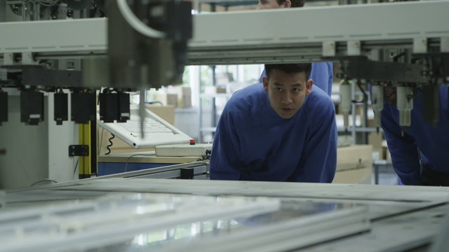 Male machine operators in a factory checking the process