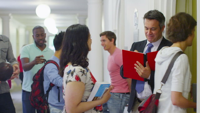 Teacher checking the register as his students enter the classroom