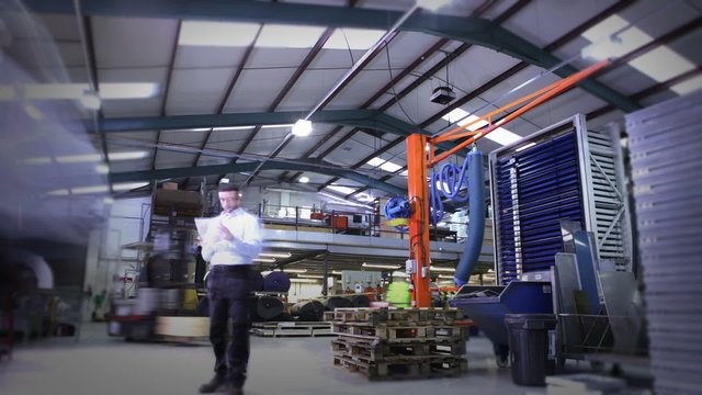 Time lapse clip of busy warehouse workers lifting and moving empty pallets