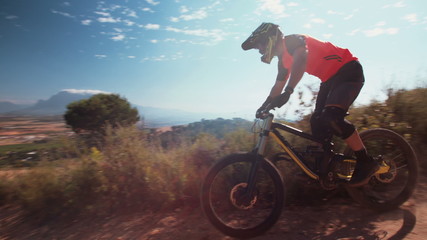 Mountain biker riding downhill on a cross country dirt path - Powered by Adobe