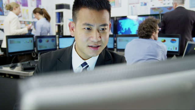 Young and ambitious stock market trader is working at his desk in a busy office