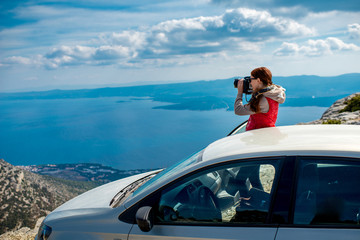Fototapeta premium Woman photographer with car on the top of mountain