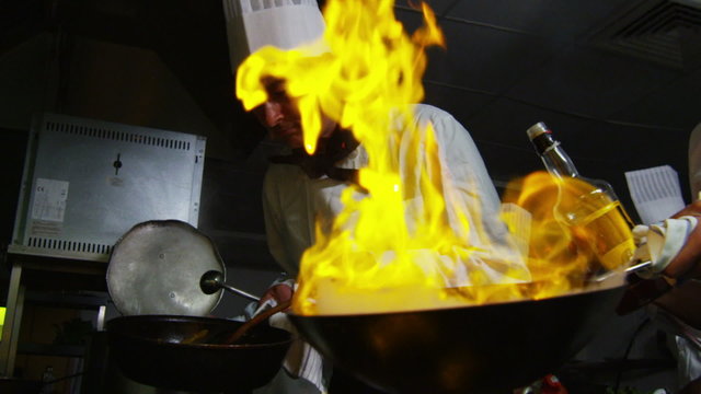 Professional chef in a restaurant kitchen cooking flambe style