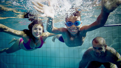 Happy and attractive mixed race family swimming underwater smiling at the camera