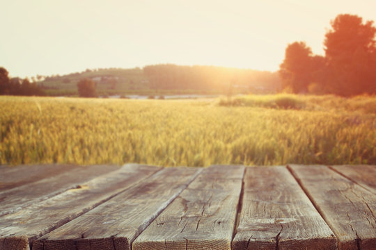 wood board table in front of field of wheat on sunset light. Rea