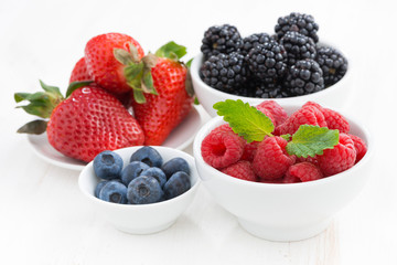 Fresh berries in bowls on a white wooden table