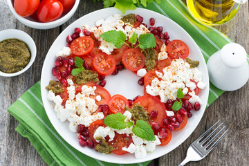 fresh salad with tomatoes, cottage cheese, pesto and pomegranate