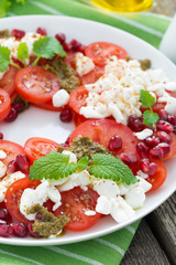 fresh salad with tomatoes, cottage cheese, pesto and pomegranate