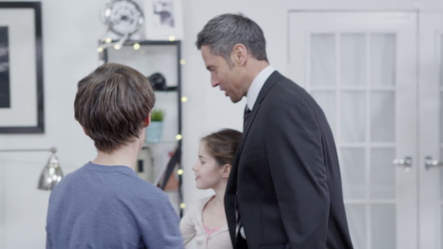 Businessman returns home from work and is greeted by his family