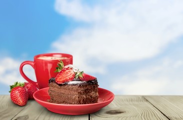 Closeup. Delicious chocolate cake with cream and berries and cup
