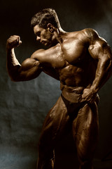 Fototapeta na wymiar Handsome muscular bodybuilder posing over dark background