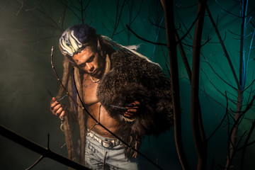 Werewolf with a skin on his skin and long nails among tree branc