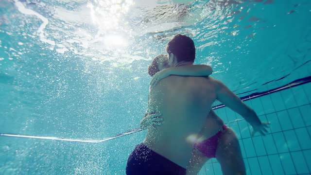 Attractive and playful couple underwater kissing and embracing