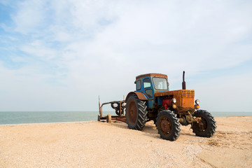 old orange tractor on the sandy beach. Azov sea. dolganka