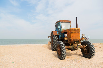 old orange tractor on the sandy beach. Azov sea. dolganka