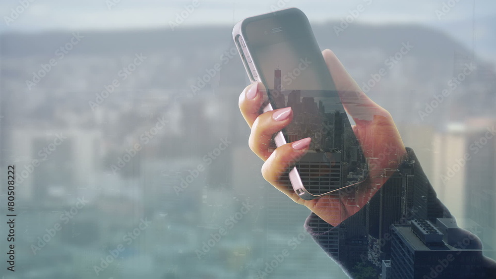 Wall mural hands using a touch screen phone with city visual background
