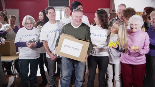 Large group of charity volunteers assemble and give big smiles into camera 