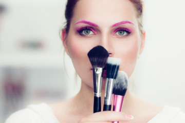 The makeup artist holds powder brushes