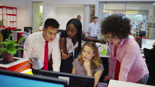 Attractive diverse business group in modern office looking at a computer screen