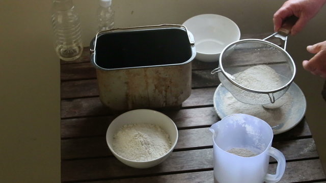 caucasian woman hands sift flour through bolter