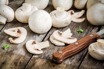 raw sliced champignons on a rustic wooden table close up