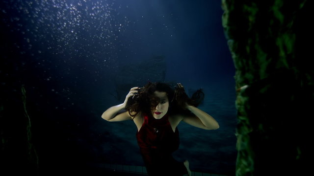Beautiful mysterious underwater woman in red dress