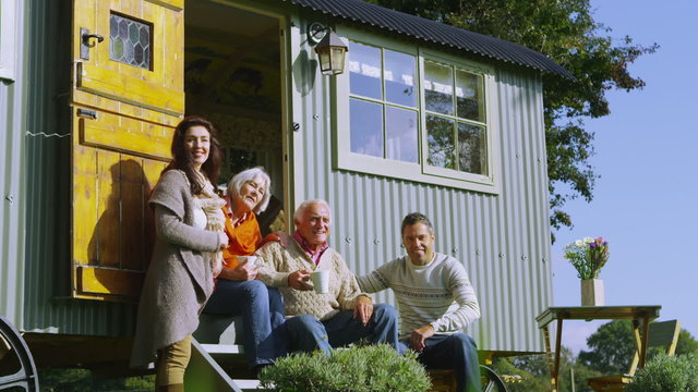 Cheerful family relaxing together outside quaint caravan in a natural setting