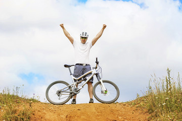 Obraz premium Winning biker on a dolomite mountain with hands up