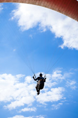 Naklejka na ściany i meble Paraglider flying on blue sky