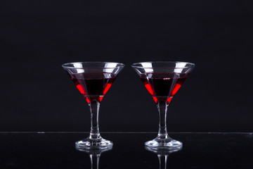 Red wine in a two glasses of martini on a black background