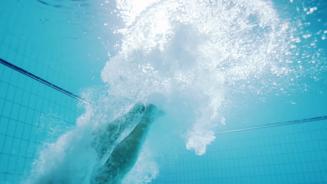 Underwater view of a professional male swimmer diving into clear blue water