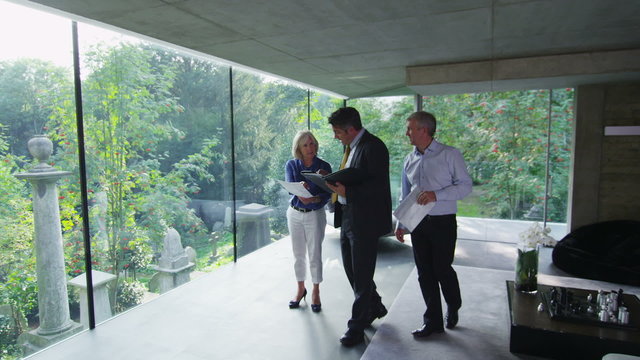 Mature couple being shown round a luxury modern home by the estate agent