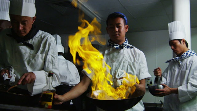 Professional chef in a restaurant kitchen cooking flambe style