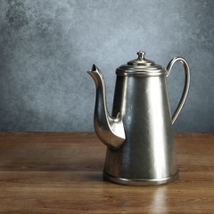 Retro coffee pot stand on wooden table behind grey wall