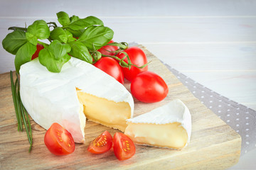 Goat cheese, cherry tomato, and basil on a wooden background
