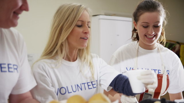 Attractive soup kitchen volunteers help to feed the homeless