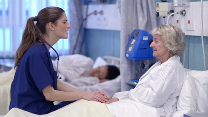 Caring nurse chats with a female patient on a hospital ward. - Powered by Adobe