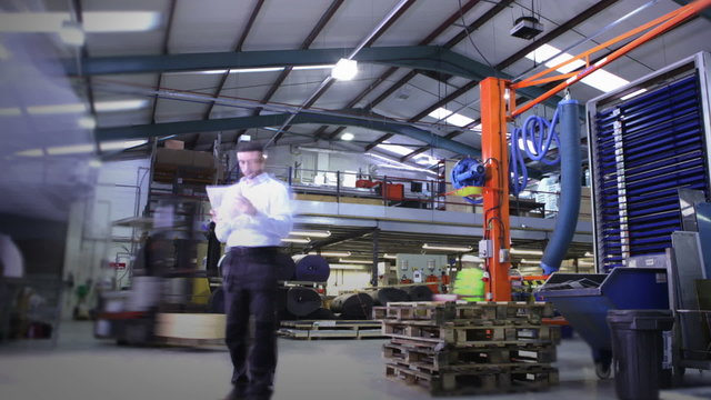 Time lapse clip of busy warehouse workers lifting and moving empty pallets