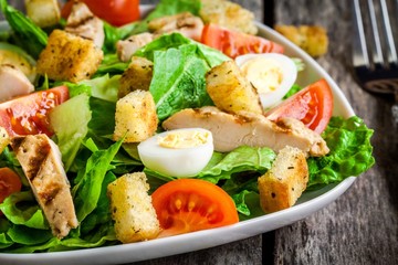 Caesar salad with cherry tomatoes and grilled chicken close up