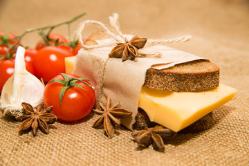 Fototapeta na wymiar Sandwich with cheese wrapped in paper, cherry tomatoes and garli