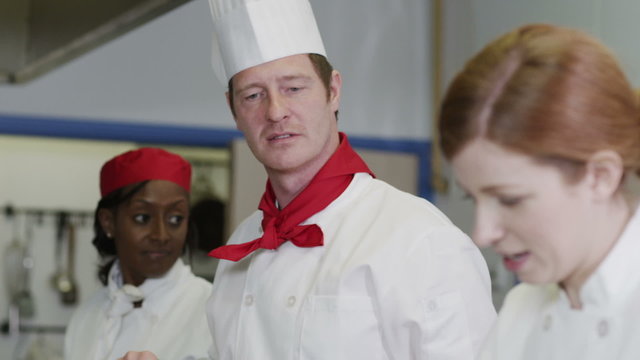 Professional team of chefs in a commercial kitchen, head chef gives instructions